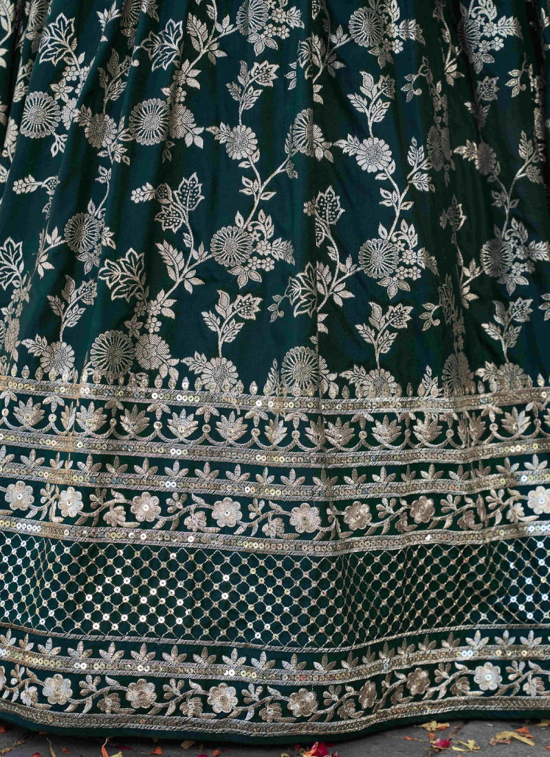 Close-up of a dark green fabric with intricate silver floral embroidery
